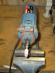 straight angle grinder mounted on a bench sharpening hedge trimmer and lawn mower blades
